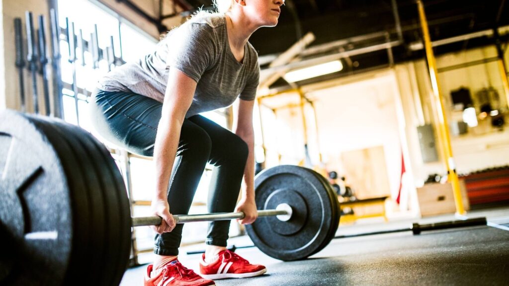 women should weight train. woman lifting weights at a gym